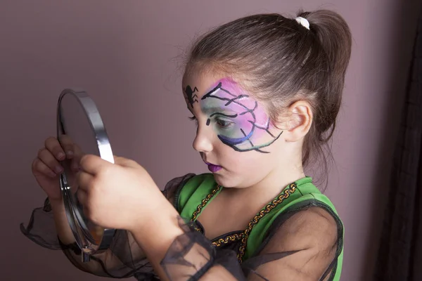 Little girl looking into the mirror after face painting session — Stock Photo, Image
