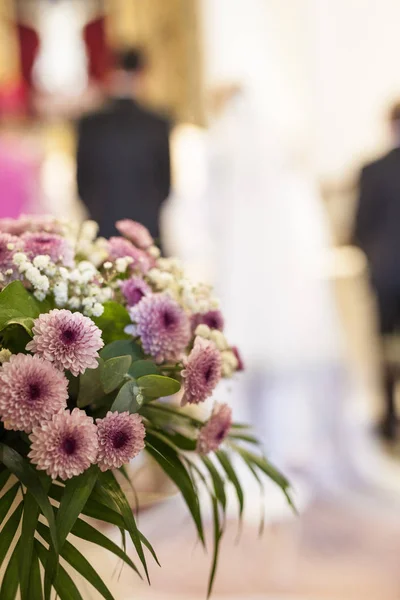 Decoración floral en el banco de la iglesia con ceremonia de boda en la parte posterior — Foto de Stock