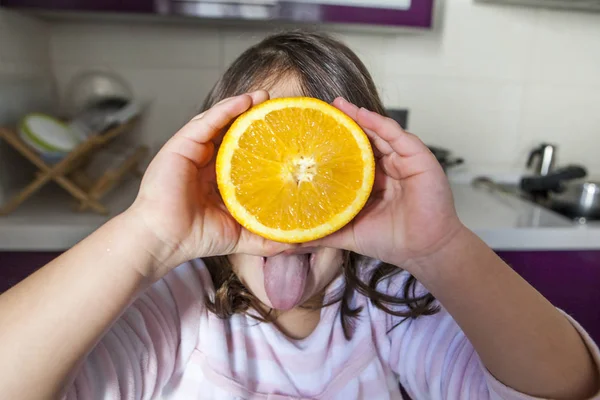 Little girl playing with orange and tongue out