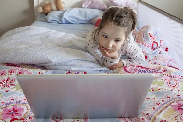 Fetiţa se uită la filme cu un laptop. Pare atent. — Fotografie, imagine de stoc