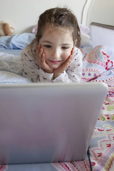 Ragazzina che guarda film con un portatile. Sembra che si stia divertendo — Foto Stock