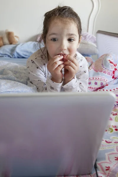 Ragazzina che guarda film con un portatile. Sembra incuriosita. — Foto Stock