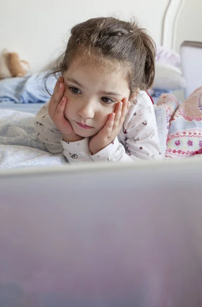 Niña viendo películas con un portátil. Se ve desatenta. — Foto de Stock