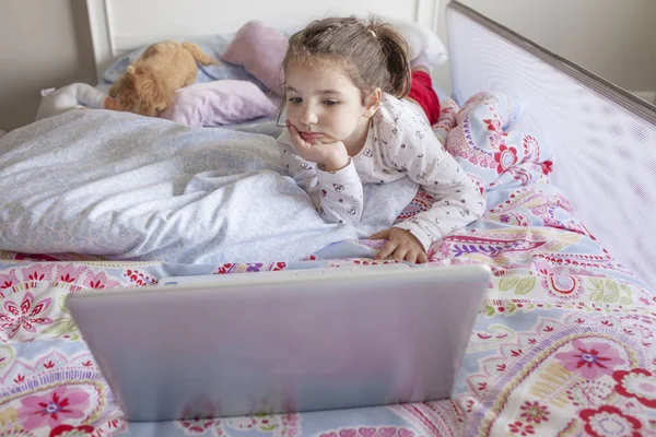 Niña viendo películas con un portátil en la cama — Foto de Stock