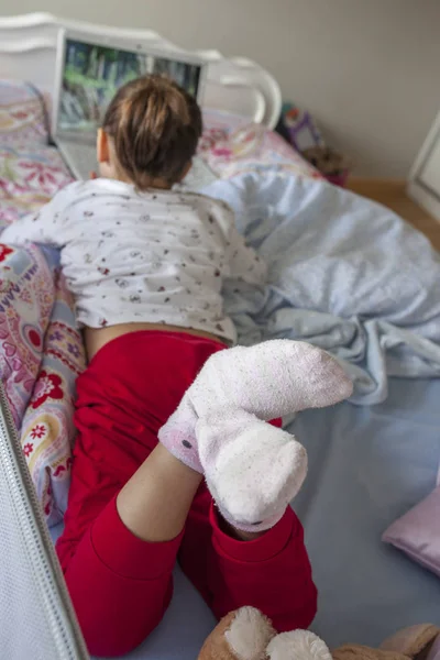Lilla flickan i sängen och titta på filmer med en laptop i Hej — Stockfoto