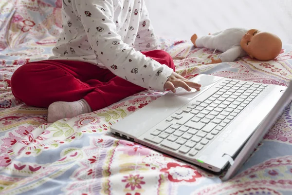 Liten flicka sitter i sängen och surfar på Internet i hans sovrum — Stockfoto