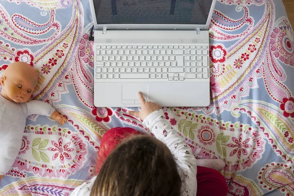 Liten flicka sitter i sängen och spela online-spel — Stockfoto