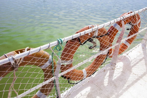 Tre salvagente a bordo del traghetto con acque fluviali verdi in fondo — Foto Stock