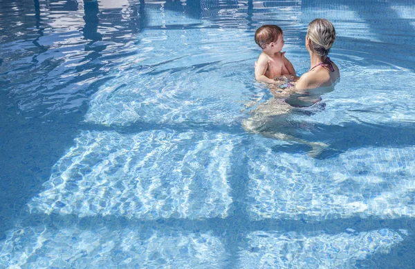 Mother playing with her baby at swimming pool indoor