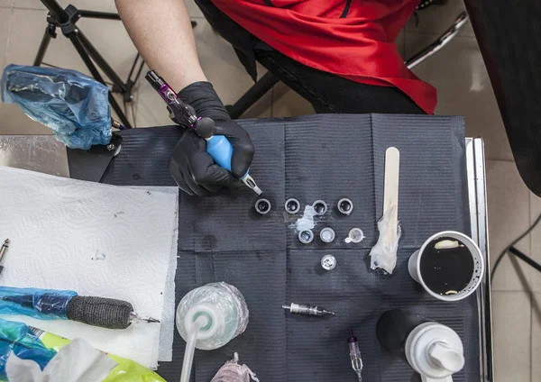 Tatovering kunstner bord, mens hun genfylder pistolen - Stock-foto