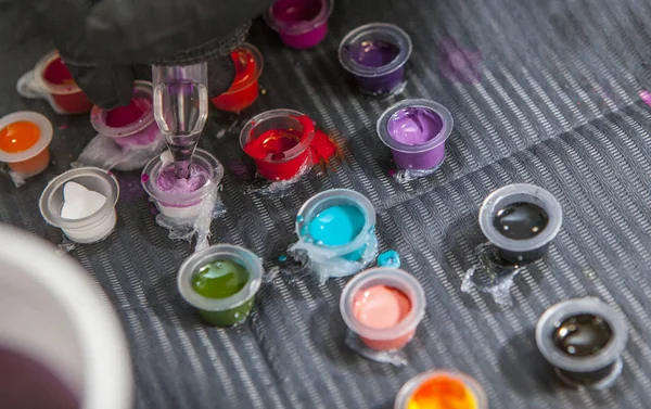 Artista del tatuaje mezclando colores en una taza pequeña para tinta — Foto de Stock