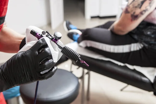 Tattoo artist clean with paper towel the gun ink machine — Stock Photo, Image