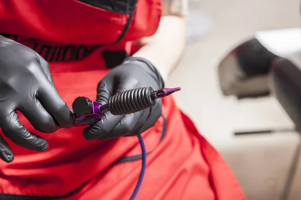 Tattoo artist adjusts the gun ink machine — Stock Photo, Image