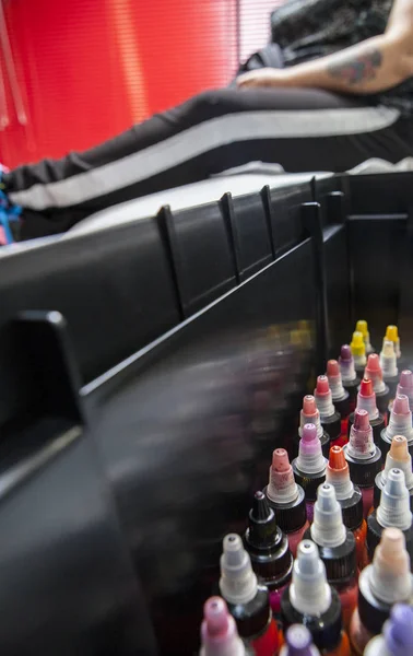 Bottiglie di inchiostro colorato del tatuaggio, in un salone del tatuaggio con costume — Foto Stock