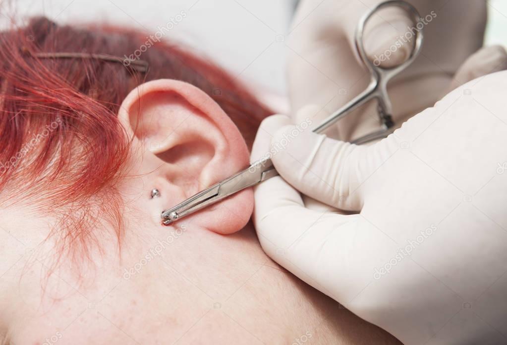 Professional placing the jewel of piercing on the ear