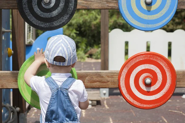 Ragazzo di 2 anni che gioca con un disco a spirale in legno al parco giochi — Foto Stock