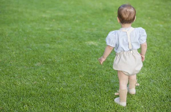 Kleiner Junge in formeller Kleidung steht über grünem Rasen — Stockfoto