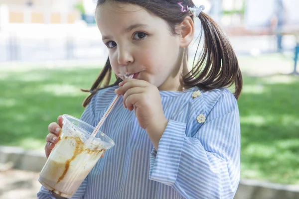 Little girl drinking milkshake at park — Stock Photo, Image