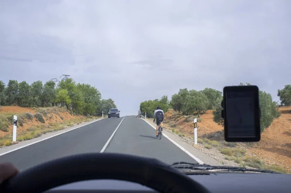 Conduciendo lentamente detrás de un ciclista por la carretera local sobre la línea sólida — Foto de Stock