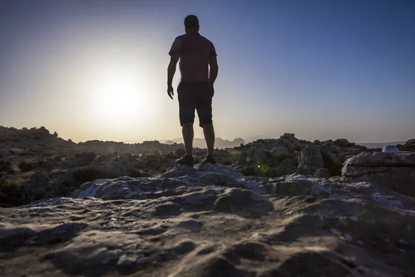 Homme regardant le lever du soleil sur un sol rocheux — Photo