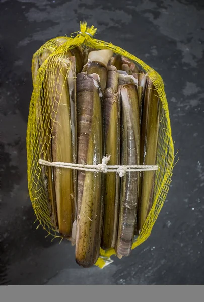 Bündel von Rasiermuscheln in geöffnetem Plastiknetz — Stockfoto