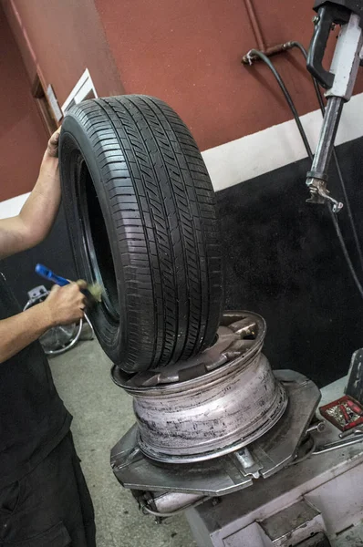 Automechaniker reicht Schmierreifen, bevor sie die Felge montieren — Stockfoto