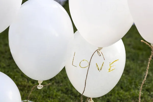 Weiße Luftballons über dem Gras sagen "Liebe" bei einem Hochzeitsempfang — Stockfoto