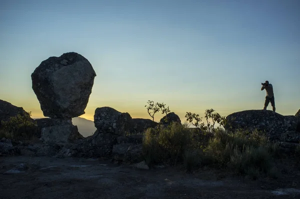 Silueta de un fotógrafo tomando el sol saliendo por encima del monte —  Fotos de Stock