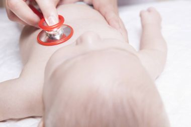 Çocuk doktoru yeni doğan bebek çocuk stetoskop ile inceliyor.