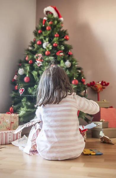 小女孩在圣诞树下打开礼物 — 图库照片