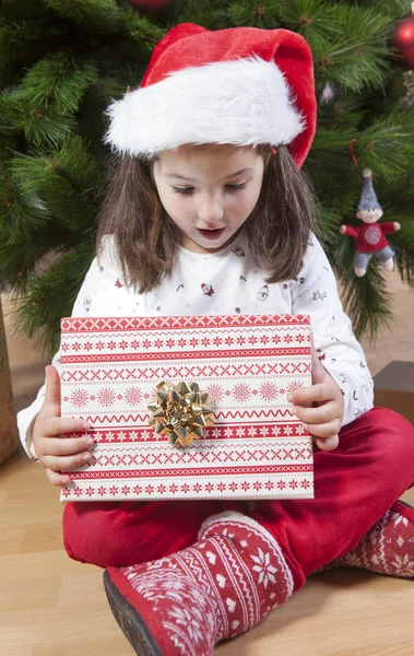 小女孩打开他礼物在圣诞树下 — 图库照片