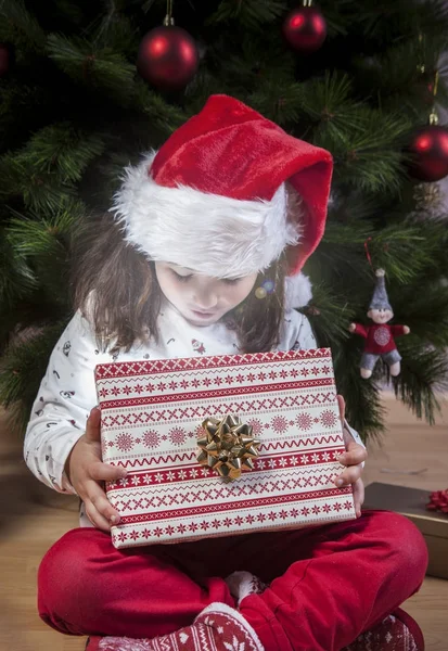 Little girl opening he present under Christmas tree Royalty Free Stock Photos