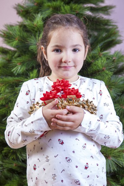 Smiling little girl with a lot of ribbons for Christmas tree dec