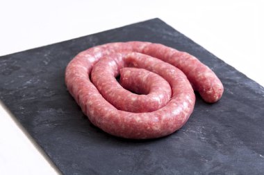 Rolled uncooked botifarra or Catalan sausage. Isolated over black slate clipart