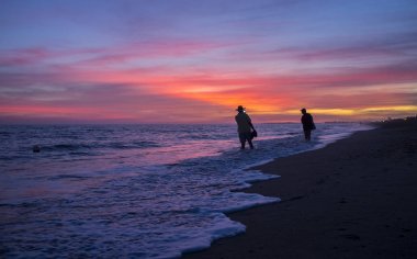 Elder tourist couple taking pictures at Islantilla beach during  clipart