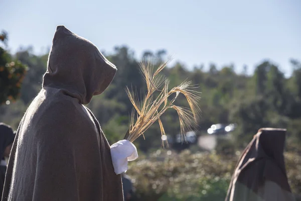 Hooded entourage members with wheat bundle offering — Stock Photo, Image