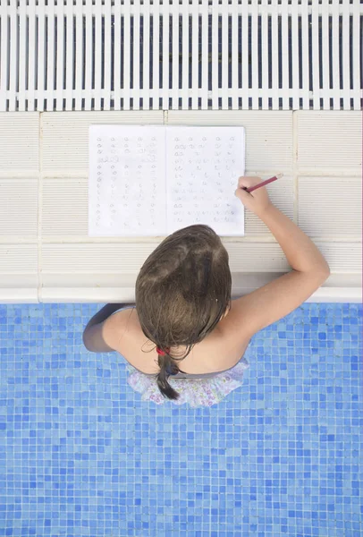 Dítě dívka dělat domácí úkoly dovolené po plavání u bazénu — Stock fotografie