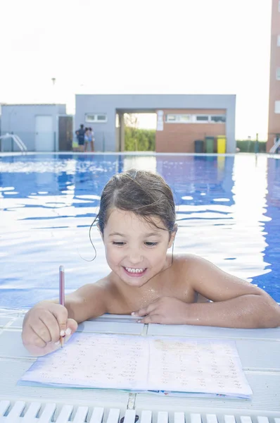 Barn tjej gör semester läxor över simning vid poolen — Stockfoto