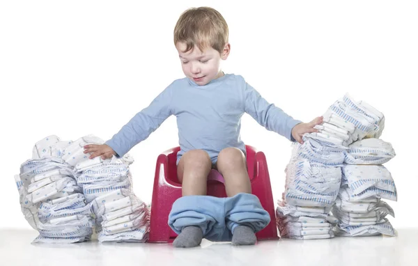 Niño feliz sentado en la olla de la cámara derribando pilas de pañales — Foto de Stock