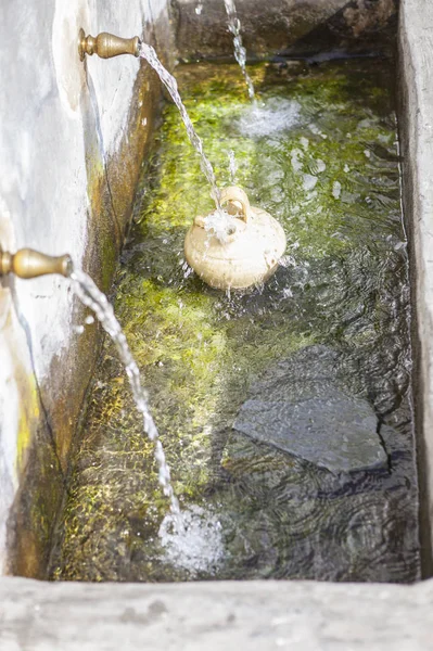 En botijo är fylld med färskvatten på offentliga fontän på Alpuja — Stockfoto