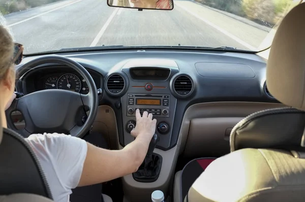 Donna regolazione radiocomando pulsante di controllo mentre si sta guidando . — Foto Stock