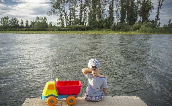 小男孩在河边玩卡车装满了金石 — 图库照片