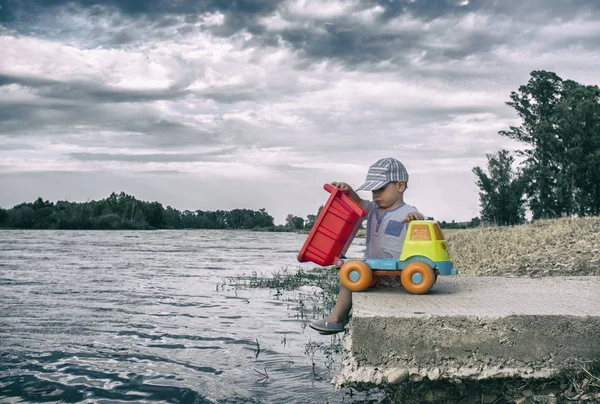 Küçük çocuk Nehri üzerinde onun Damper kamyon boşaltma — Stok fotoğraf