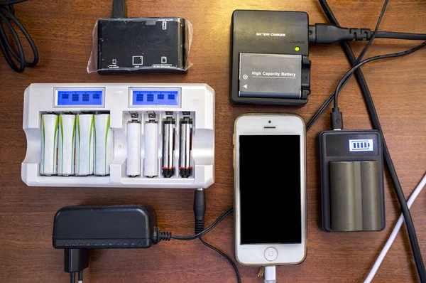 Много зарядных устройств, мобильных батарей, фотоаппаратов — стоковое фото