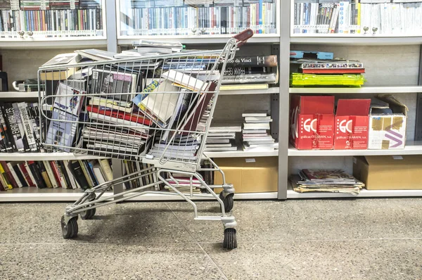 Overloaded shopping cart full of books at technical processing a — Stock Photo, Image