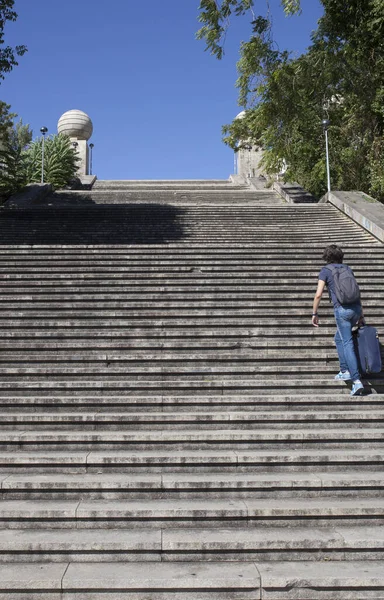 Joven turista subiendo las escaleras con su pesada maleta —  Fotos de Stock