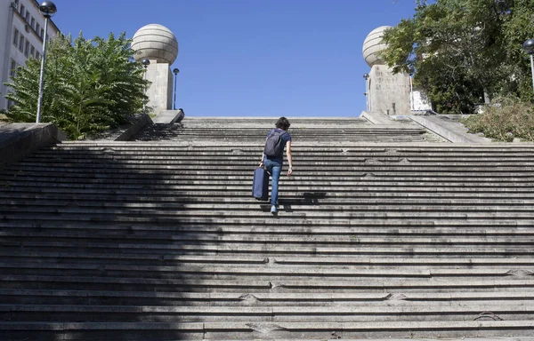 Young tourist woman going up the stairs with her heavy suitcase — Stock Photo, Image