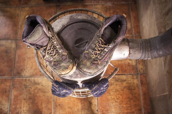 Wet used boots and socks drying over firewood stove — Stock Photo, Image
