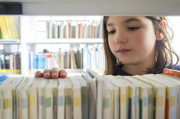 Giovane ragazza che seleziona i libri dalla libreria biblioteca — Foto Stock