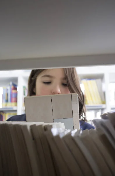 Young girl selecting books from library bookshelf — Stock Photo, Image